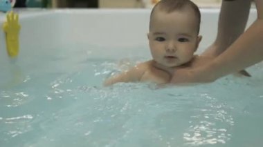 Havuzda küçük bir çocuk var. Yüzmeyi öğreniyorum. Meme bebeği. Annenin elleri. - Su. Sağlığa. Spor haberleri. İlaç.. 