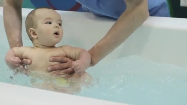 En liten pojke i poolen. Att lära sig simma. Bröstbebis. Mödrar händer. Vatten. Hälsa. Idrott. Medicin. — Stockvideo