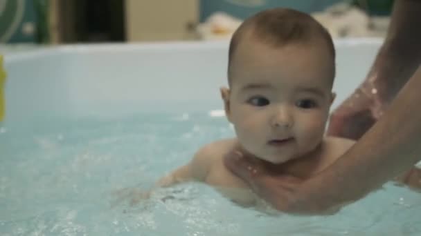 A little boy in the pool. Learning to swim. Breast baby. Mothers hands. Water. Health. Sports. Medicine. — Stock Video