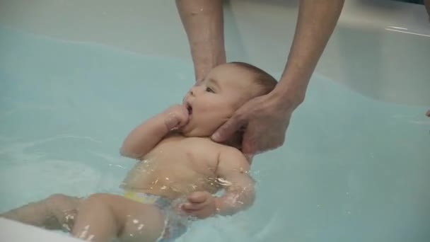 Un ragazzino in piscina. Imparare a nuotare. Bambino al seno. Le mani delle madri. Acqua. Salute. Sport. Medicina . — Video Stock