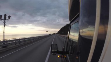 Araba köprünün üzerinde. Kokpitten görüntü. Bu boş bir yol. İnsan yok. Doğru yoldayız. Yol boyunca sokak lambaları. Gün batımı. 