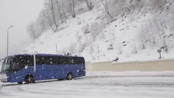 Egy kék utasszállító busz megfordul az úton. Tél. Hófehérke. Ez nem rejtély. Rossz idő. — Stock videók