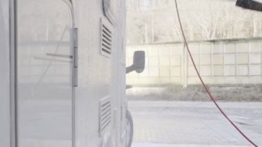 Avrupa uyruklu genç bir adam araba yıkamada araba yıkıyor. Mevsimlik karavan, motorlu taşıt temizleme, basınç makinası. Karavan kampçısı. Beyaz Erkekler