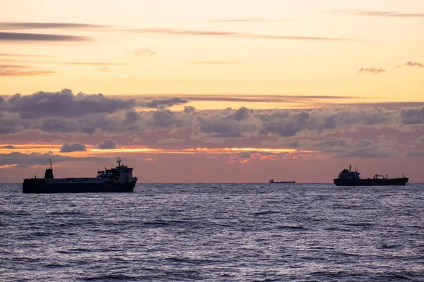 Denizin üzerinde turuncu gün batımı. Endüstriyel gemi yolda. Gökyüzünde güzel bulutlar. Kargo taşımacılığı. Denizci