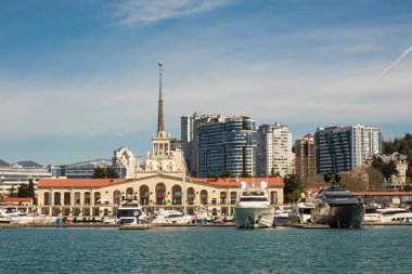 Sochi, Rusya - 03.04.2020 Soçi Limanı. Yatlar ve gemiler limanda. Tarihi bir bina. Deniz kenarındaki yüksek modern evler. Güneşli bir gün.. 