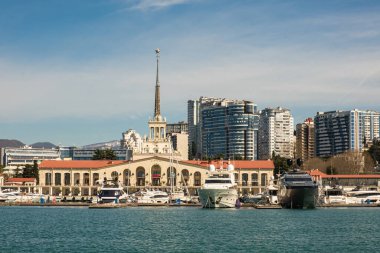 Sochi, Rusya - 03.04.2020 Soçi Limanı. Yatlar ve gemiler limanda. Tarihi bir bina. Deniz kenarındaki yüksek modern evler. Güneşli bir gün.. 