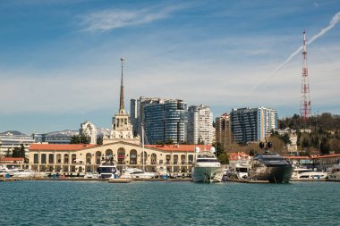 Sochi, Rusya - 03.04.2020 Soçi Limanı. Yatlar ve gemiler limanda. Tarihi bir bina. Deniz kenarındaki yüksek modern evler. Güneşli bir gün.. 