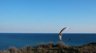 Soçi, Rusya - 20.04.2020 Açık mavi gökyüzünde uçan sıra dışı paraglider. Eğitmeni olan adam paraşütle uçar. 4k, ağır çekim..
