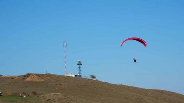 ソチ、ロシア- 20.04.2020澄んだ青い空に向かって飛ぶ極端なパラグライダー。教官との男はパラシュートで飛ぶ。4k,スローモーション. — ストック動画