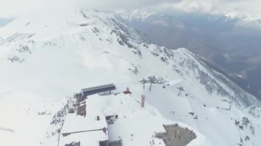 Yüksek karlı dağlar. Kayak merkezi. Bulutlu. Hava fotoğrafçılığı videosu. Yukarıdan manzara. Kar yağıyor. Krasnaya Polyana. Soçi..