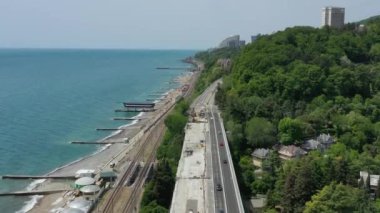 Deniz kıyısında bir yol. Deniz kenarı manzarası. Yeşil ağaçlar. Kumsal. Yaz. Panorama. Hava videosu. Soçi. Rusya. 