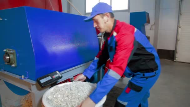 Arbeiter lädt geschnittenes Plastik in automatisierte Kunststoff-Recyclingmaschine — Stockvideo