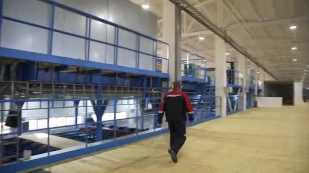 Ipari belső tér egy modern fűrészmalomban. Egy védőruhás favágó sétál át egy modern gyáron egy favágó között. Faalapú fatermelés. Fafeldolgozás. — Stock videók