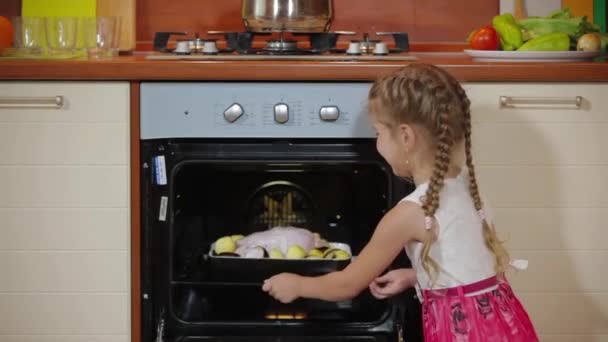 Seule mignonne petite fille cuisinant dans la cuisine, petite fille aidant maman à cuisiner des aliments savoureux préparant le dîner. Cuire le poulet rôti au four électrique — Video