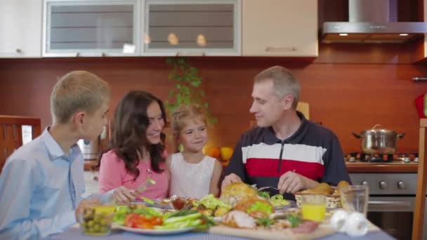 Jonge familie genieten van maaltijd rond de tafel thuis. — Stockvideo