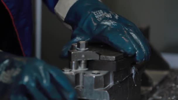 La fresadora CNC de metalurgia produce detalles de metal en fábrica. El trabajador con guantes azules fija la pieza de trabajo en la máquina. Fresadora metalúrgica. Produce detalles metálicos en una fábrica . — Vídeos de Stock