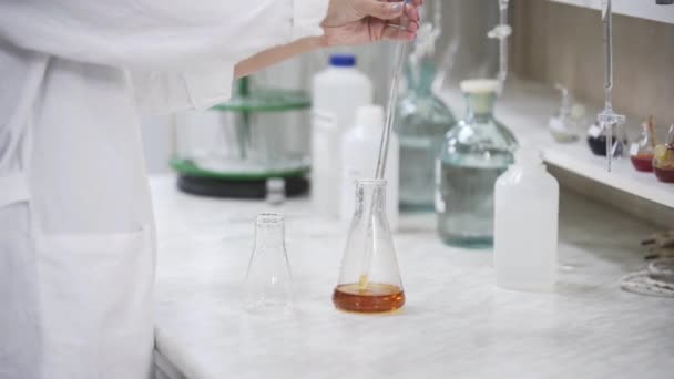 带着长笛的女科学家在酒厂实验室研究人员中分析液体。实验室设备上威士忌样品的分析. — 图库视频影像