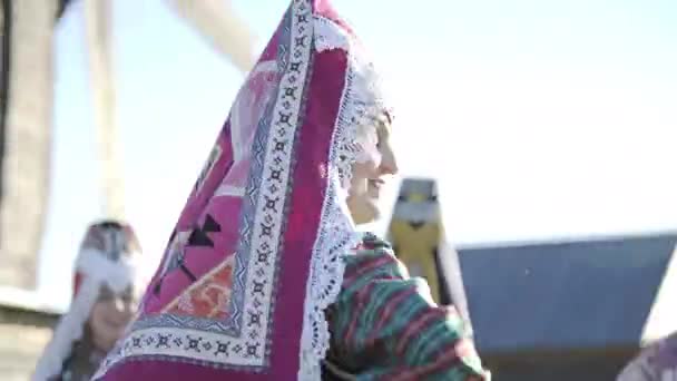 Folklore ensemble indigenous people dancing in traditional clothing outdoor on traditional antique wooden windmill background. Group of happy people wearing national Finno Ugric clothes at sunny day. — Stock Video