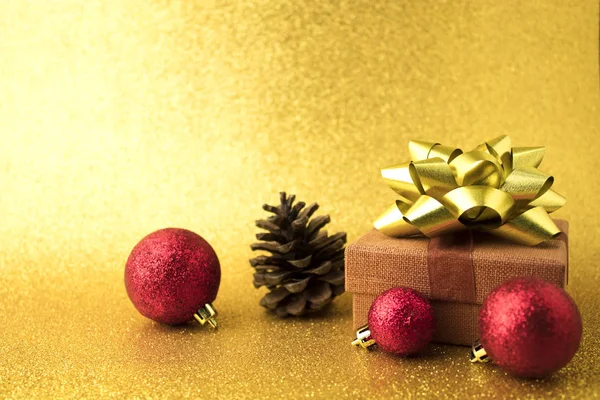 Подарок с золотым луком и шар декора с шишкой — стоковое фото