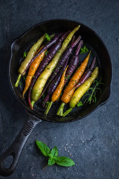 Жареная радужная морковь на сковороде — стоковое фото
