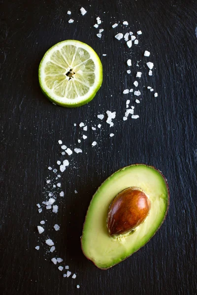 Avocado, limoen en zee zout op zwarte achtergrond — Stockfoto