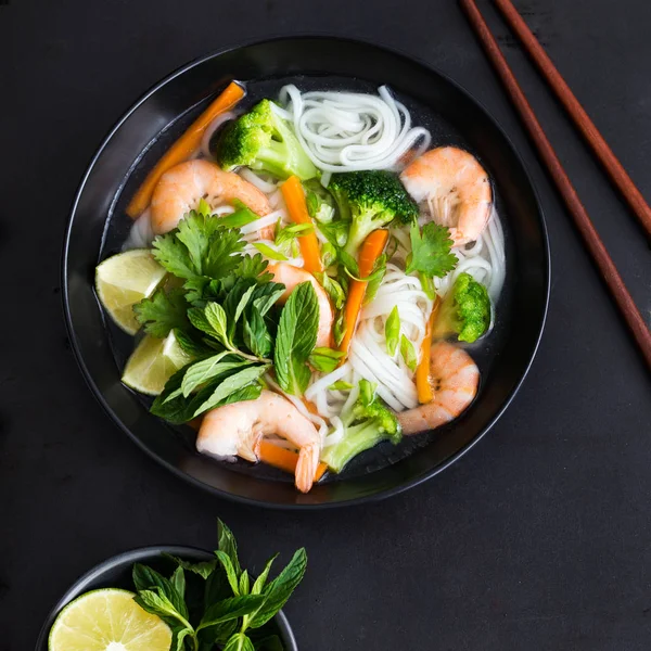 Азиатская рисовая лапша, креветки и овощной суп в миске — стоковое фото