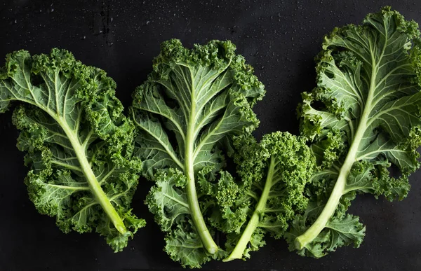 Fresh green organic kale leaves on dark background — Stock Image Fresh green organic kale leaves on dark background Royalty Free Stock Photos
