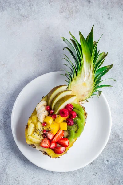 Delicious fruit salad served in fresh pineapple on white plate — Stock Photo, Image