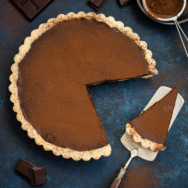 Chocolate e tarte de caramelo no fundo azul escuro — Fotografia de Stock