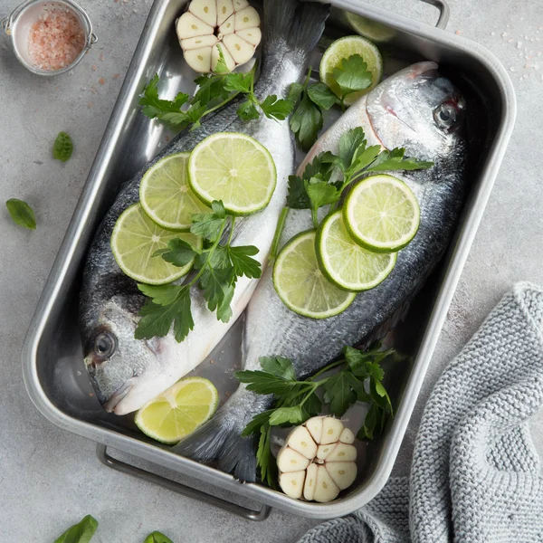 Dos pescados dorados crudos con lima y perejil listos para cocinar —  Fotos de Stock