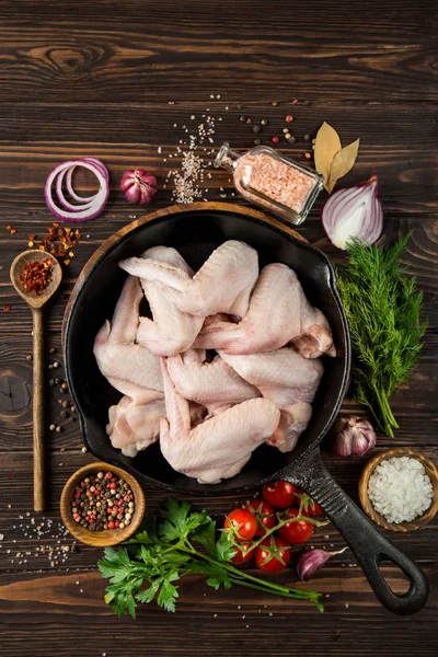 Ali di pollo crude su padella in ghisa con spezie ed erbe aromatiche, prepar — Foto Stock