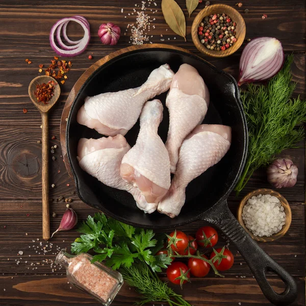 Rauwe kip benen op gietijzeren pan met specerijen en kruiden — Stockfoto