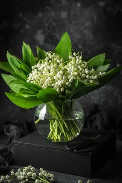 Lily of the valley flowers in glass vase, black background, — Stock Photo, Image