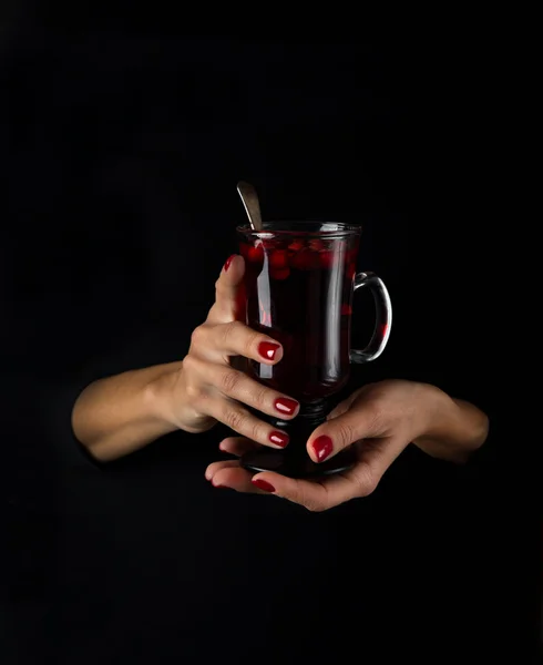 Kvinnliga händer som håller glas med varma tranbär te — Stockfoto