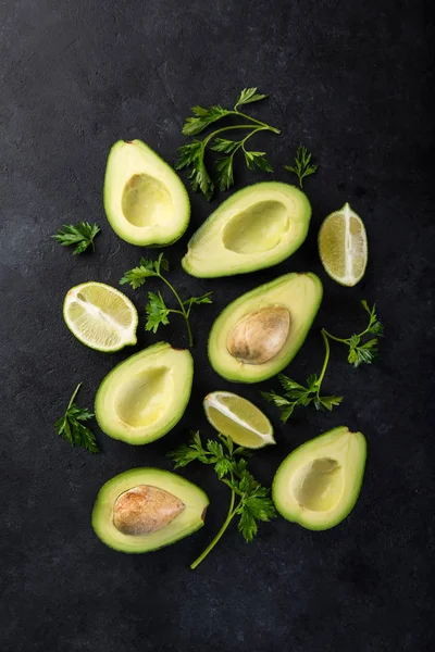 Avocado, lime and parsley on black background — Stock Photo, Image