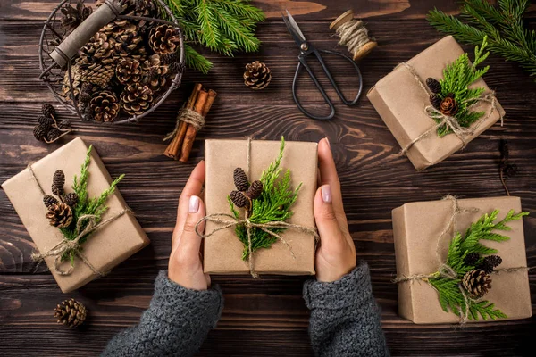 Manos de mujer sosteniendo regalos de Navidad o Año Nuevo envueltos en kra —  Fotos de Stock