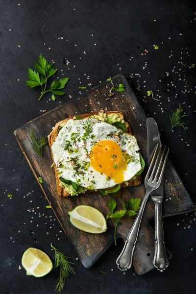 Toast with avocado, spinach and fried egg on wooden cutting boar — Stock Photo, Image