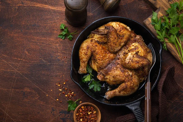 Frango frito inteiro tabaka na panela de ferro fundido, velho backgrou de madeira — Fotografia de Stock