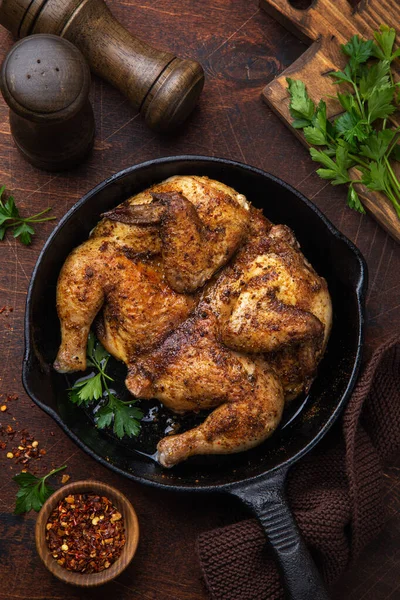 Frango frito inteiro tabaka na panela de ferro fundido, velho backgrou de madeira — Fotografia de Stock