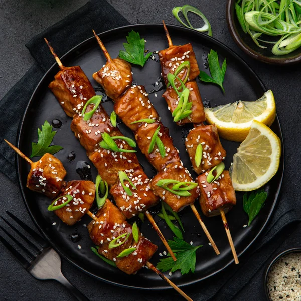 Pinchos de salmón teriyaki picantes en plato negro — Foto de Stock