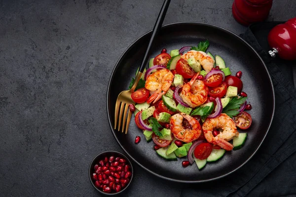 Жареные креветки и овощной салат на черной тарелке — стоковое фото