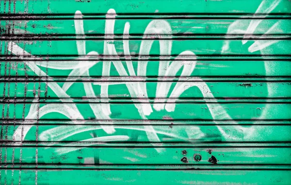 Lukkede skodder dekket med graffiti og grønn bakgrunn . – stockfoto
