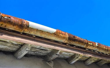 A broken gutter on the roof of a house clipart