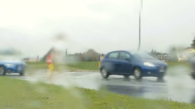 Panoramik döner kavşak trafik, şiddetli yağmur ıslak asfalt ve yağmur ile su sıçramalarına penceresinde.