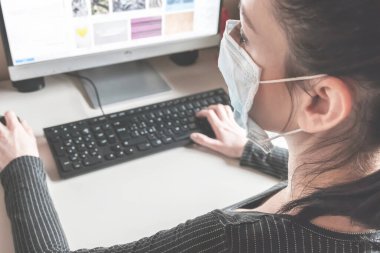 Koruyucu maske takarak evden çalışan genç bir iş kadını. Coronavirus. Koronavirüs için karantinada koruyucu maske takan bir iş kadını. Evden çalışmak.