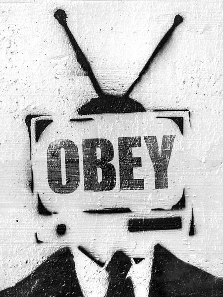 TV head with message OBEY. Addicted man holding vintage tv instead of head. Television manipulation and brainwashing concept. Mass media propaganda control.