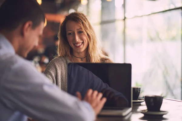 woman looking at man with laptop in cafe