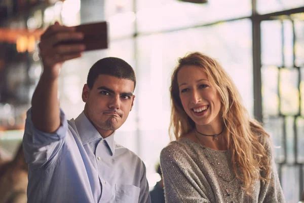 Mies naisen kanssa tekemässä selfie kahvilassa — kuvapankkivalokuva