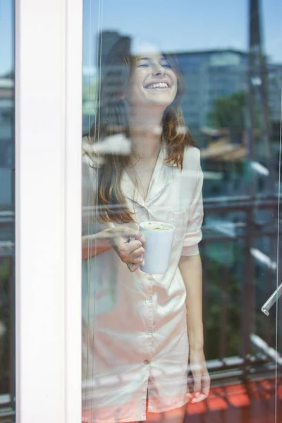Χαμογελαστή γυναίκα κοντά σε παράθυρο — Φωτογραφία Αρχείου