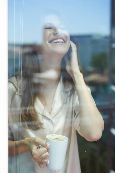 Χαμογελαστή γυναίκα κοντά σε παράθυρο — Φωτογραφία Αρχείου